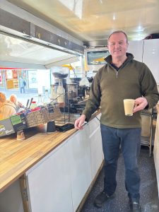 Rob holding cup of coffee in trailer