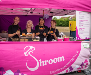 four ladies stood in a bright pink food cart